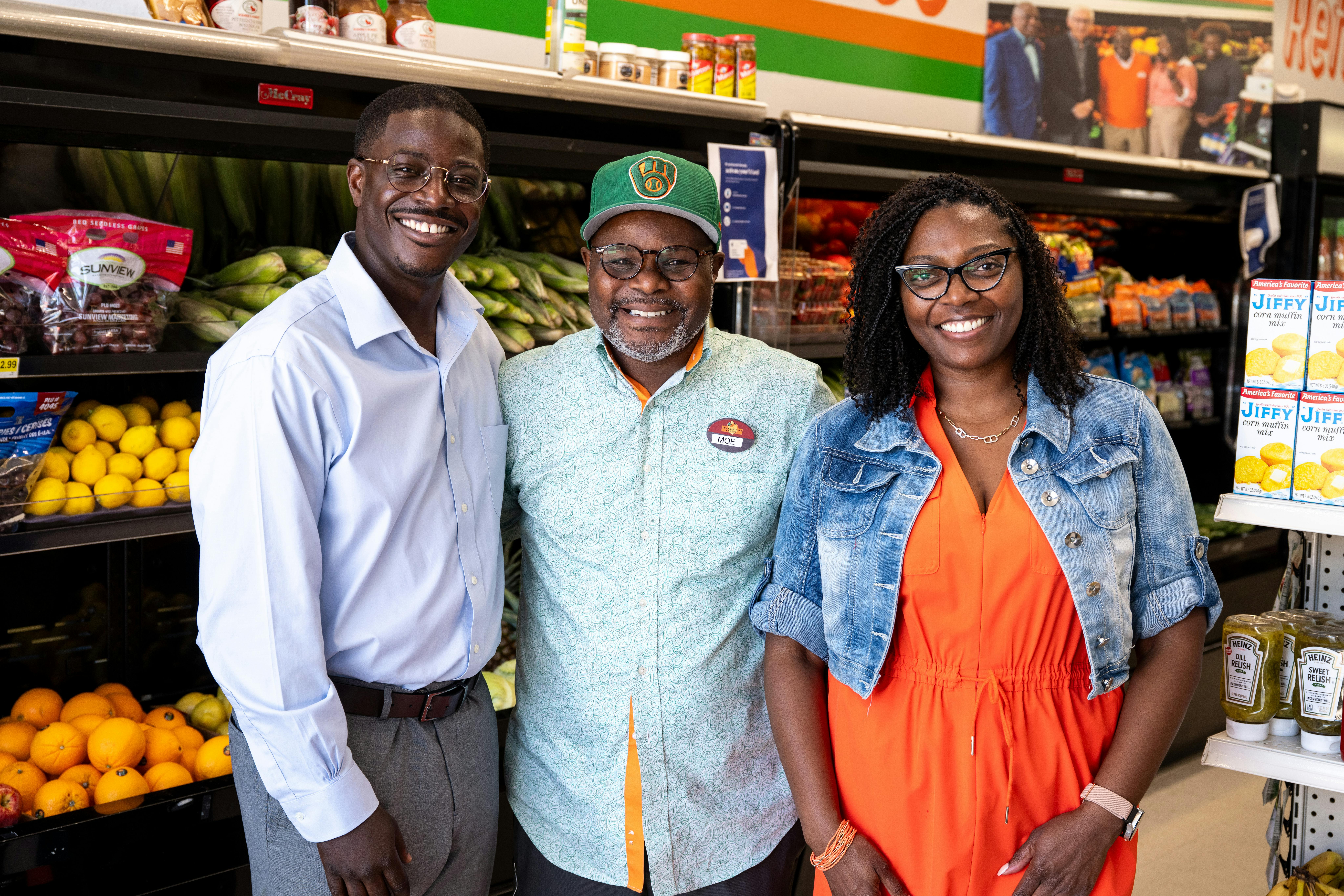 A photo of David smiling with two others in a grocery store
