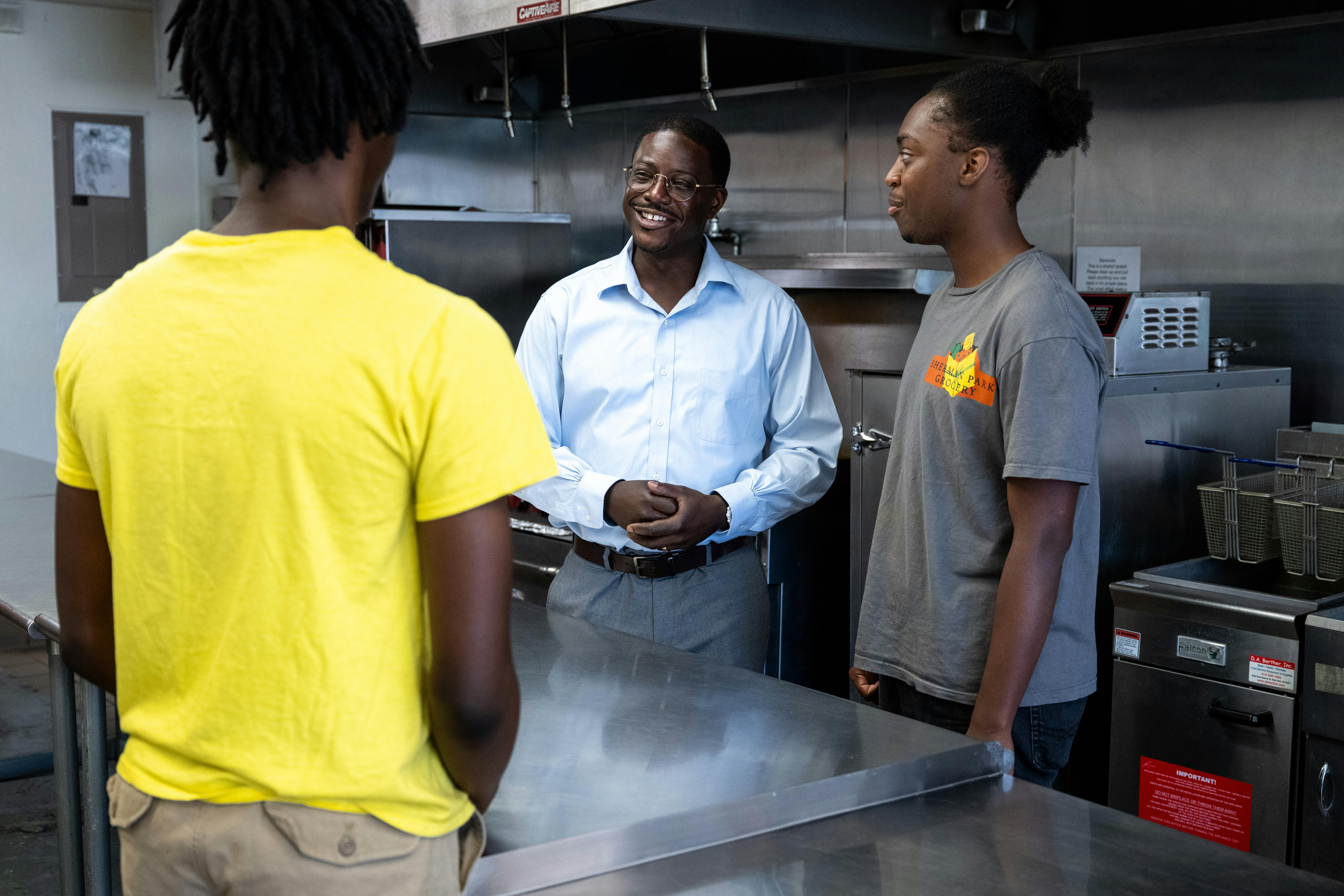 A photo of David talking to two people in a restaurant kitchen