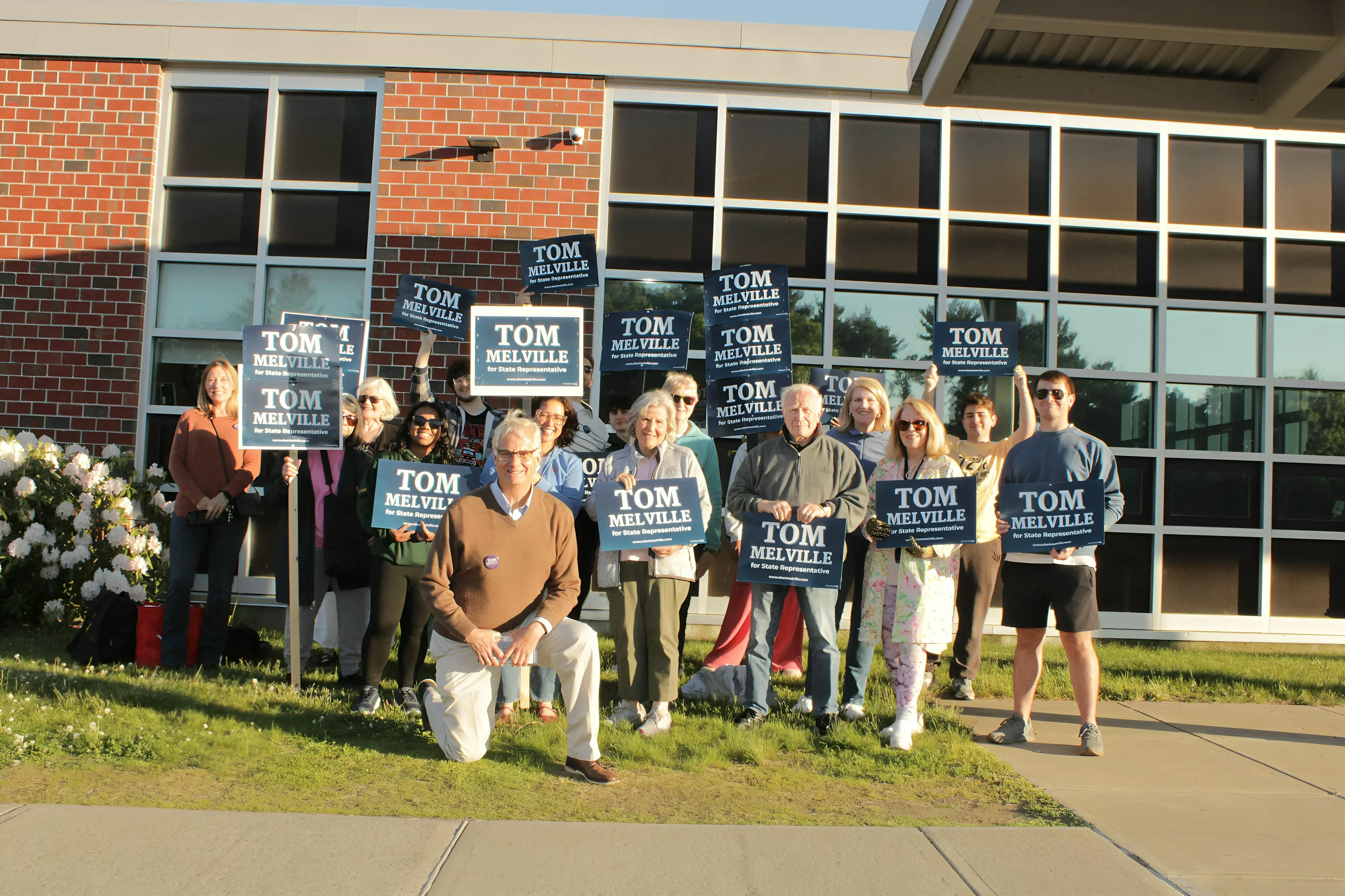 group of people holding Tom Melville signs