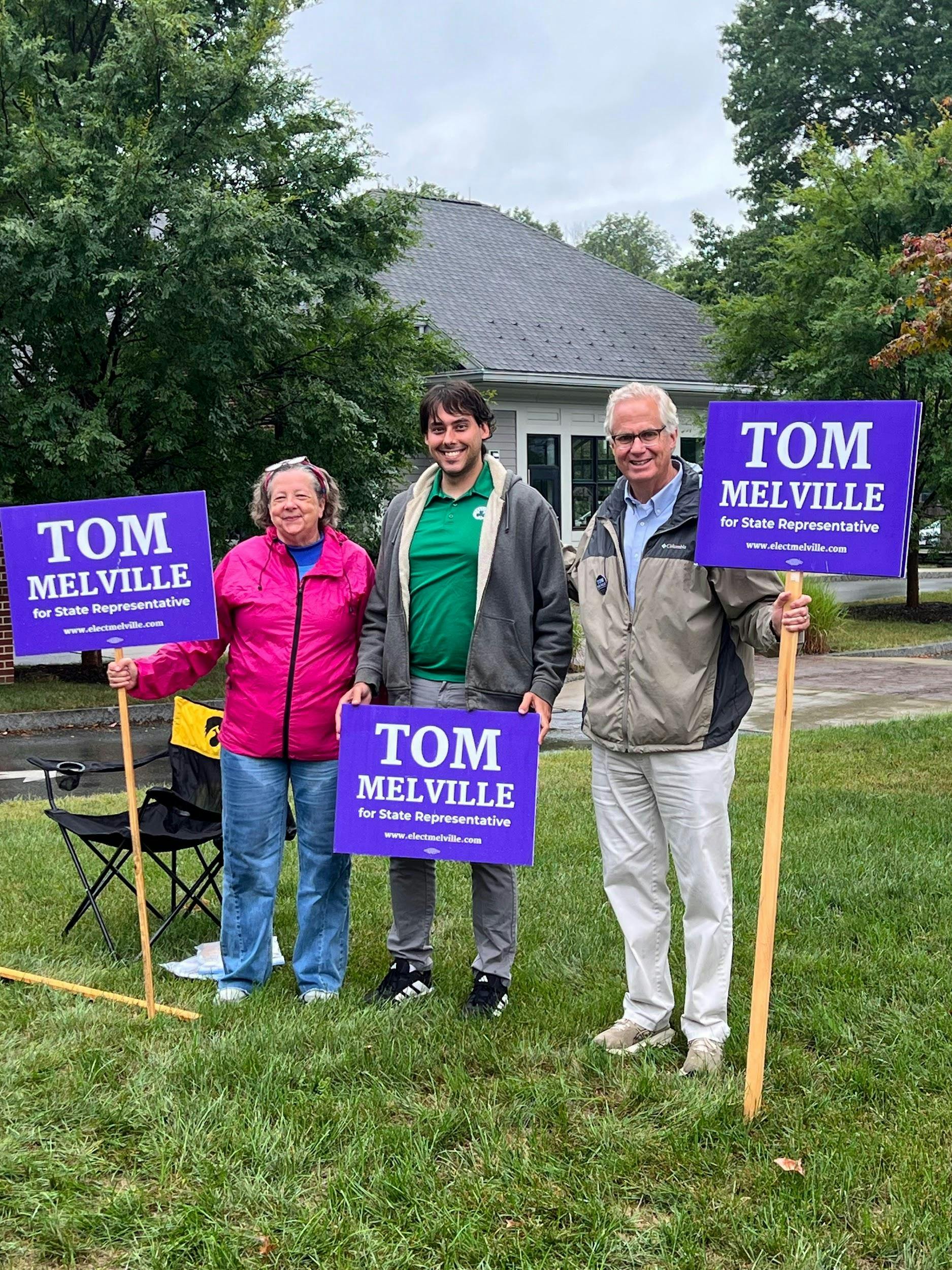 three people holding Tom Melville signs