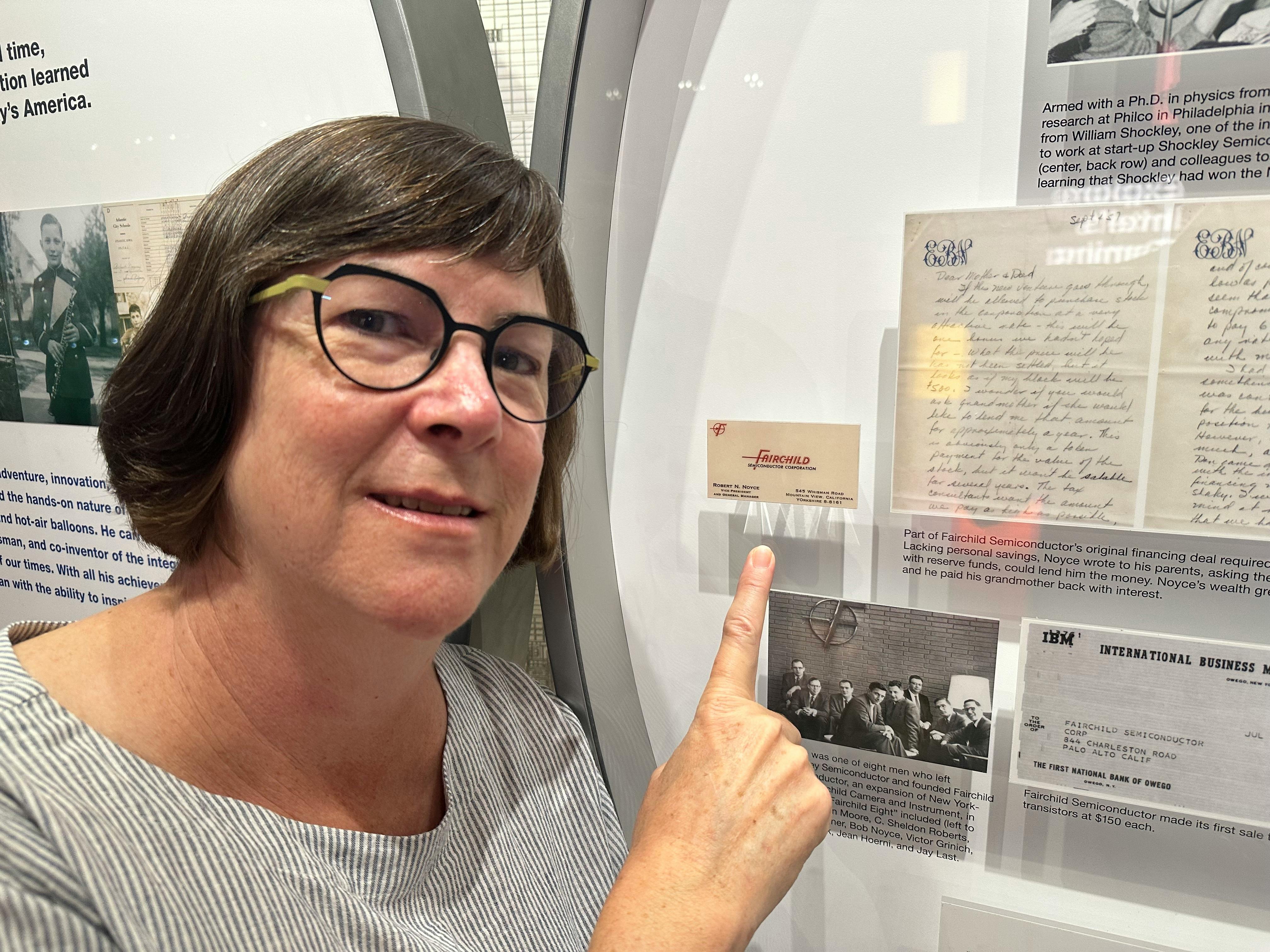Linda pointing at a Fairchild Electronics business card