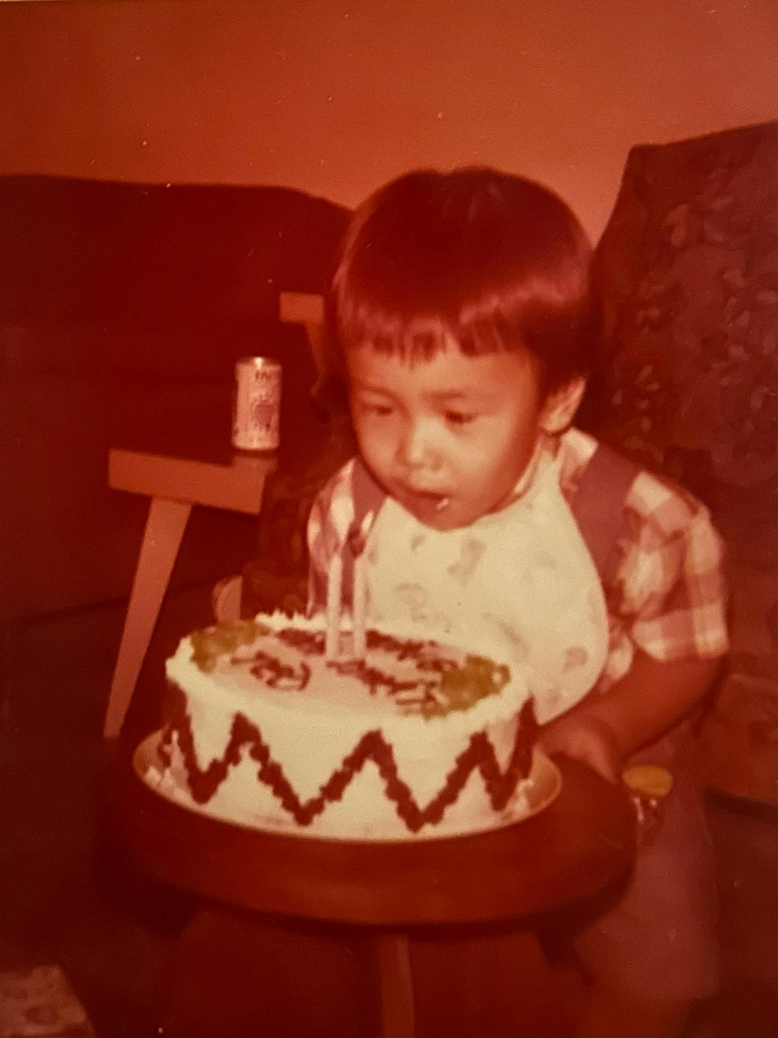 Candidate Dr. Quy Tran as a toddler sitting in front of a birthday cake.