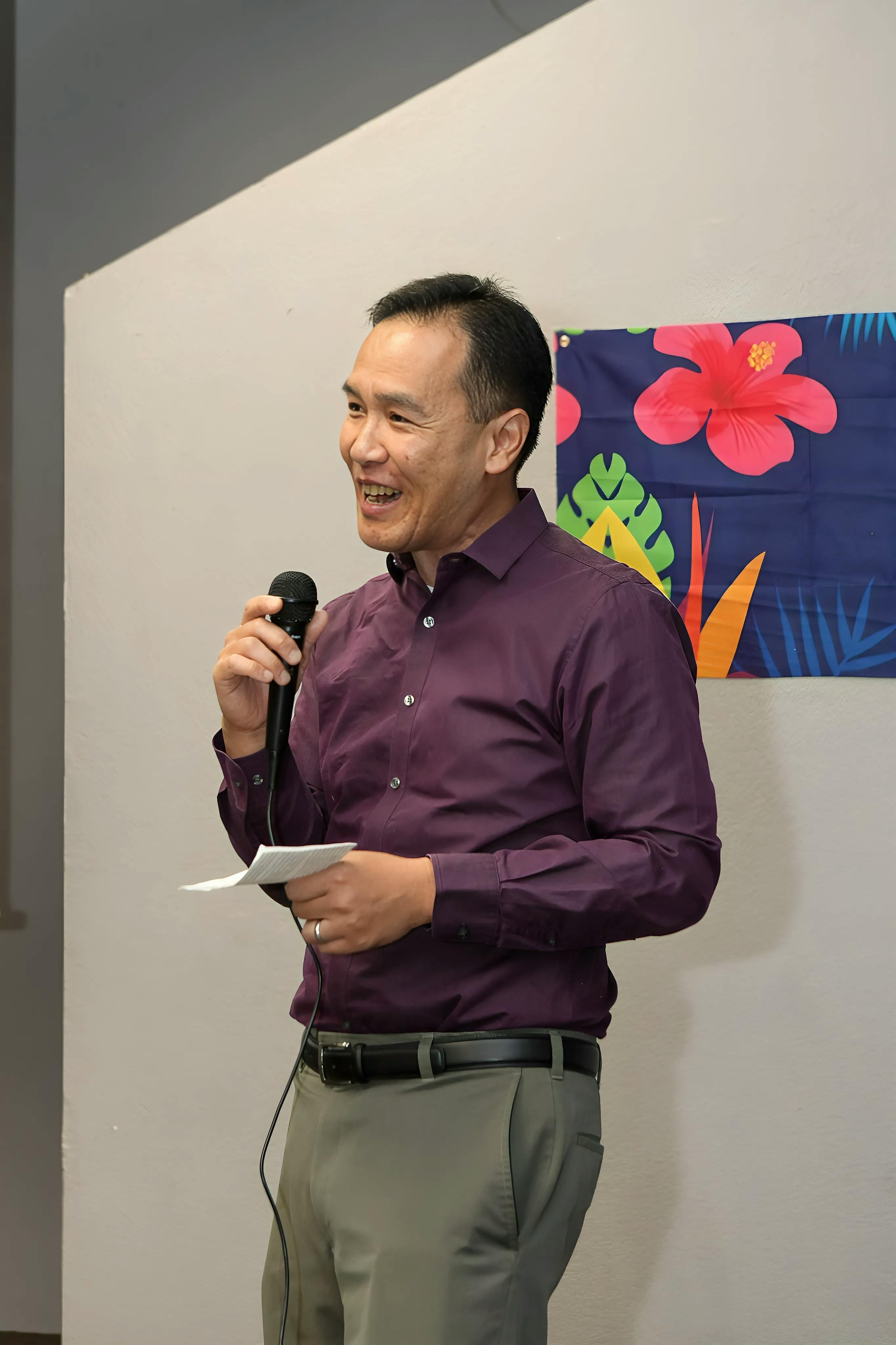 Candidate Dr. Quy Tran speaking into a microphone