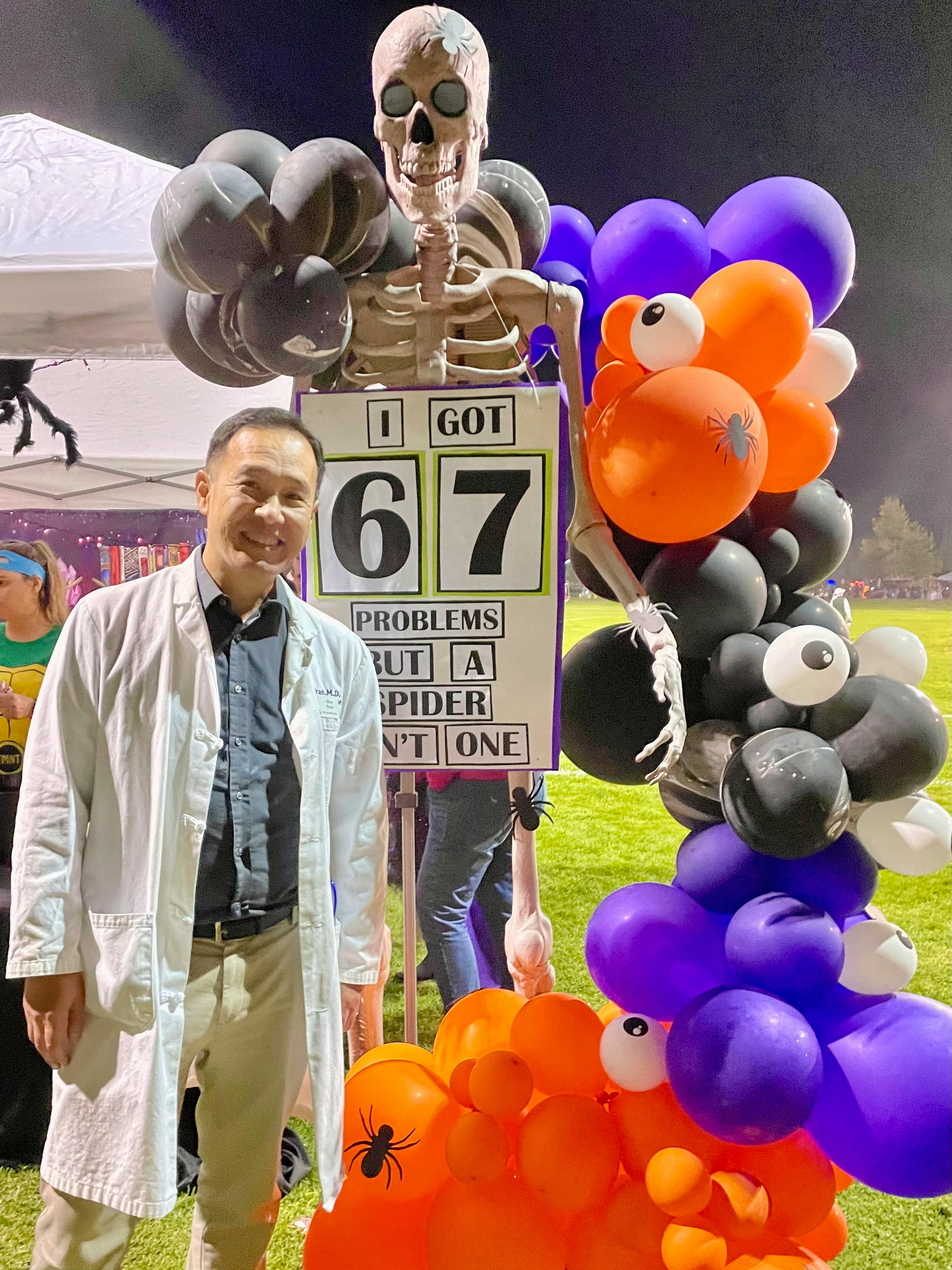 Candidate Dr. Quy Tran wearing a white coat smiling into the camera at the Haunted Trail Halloween Event for the City as hosted by the Pleasant Hill Recreation and Park District