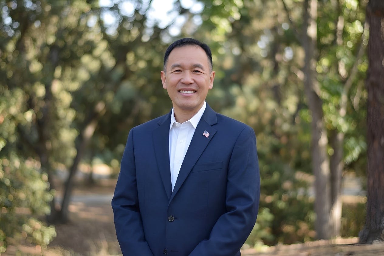 Portrait at Rodgers Smith Park in Pleasant Hill, CA of City Council Candidate Dr. Quy Tran. Dr. Tran has dark hair and is smiling. He is wearing a dark blue suit.