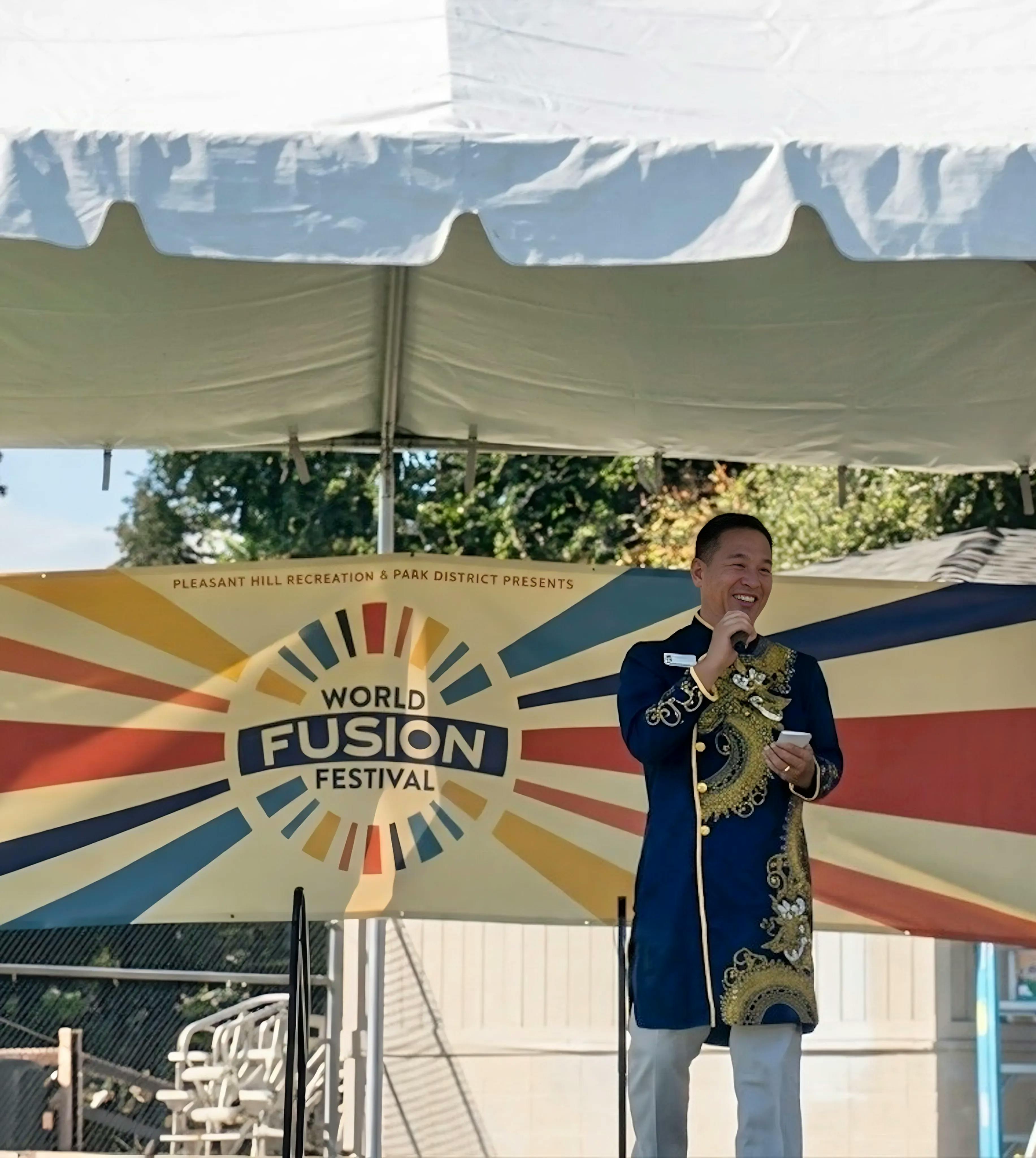 Dr. Quy Tran wearing traditional Áo gǎm on stage at World Fusion Festival