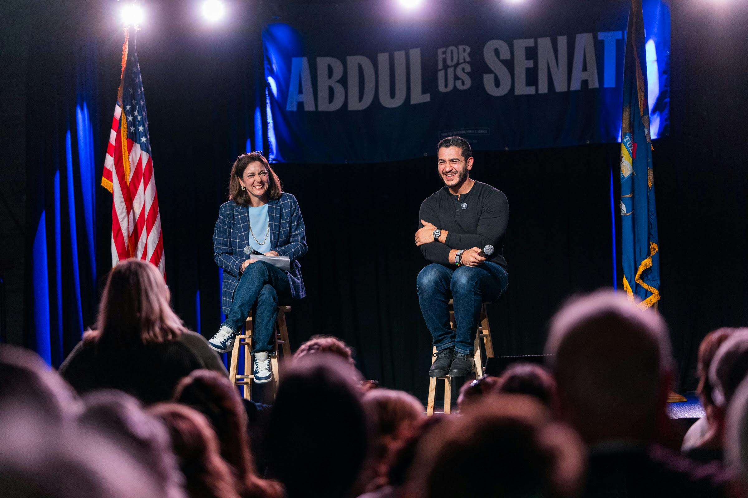End Citizens United President Tiffany Muller and Michigan Senate candidate Abdul El-Sayed sit on stage smiling in front of an audience.