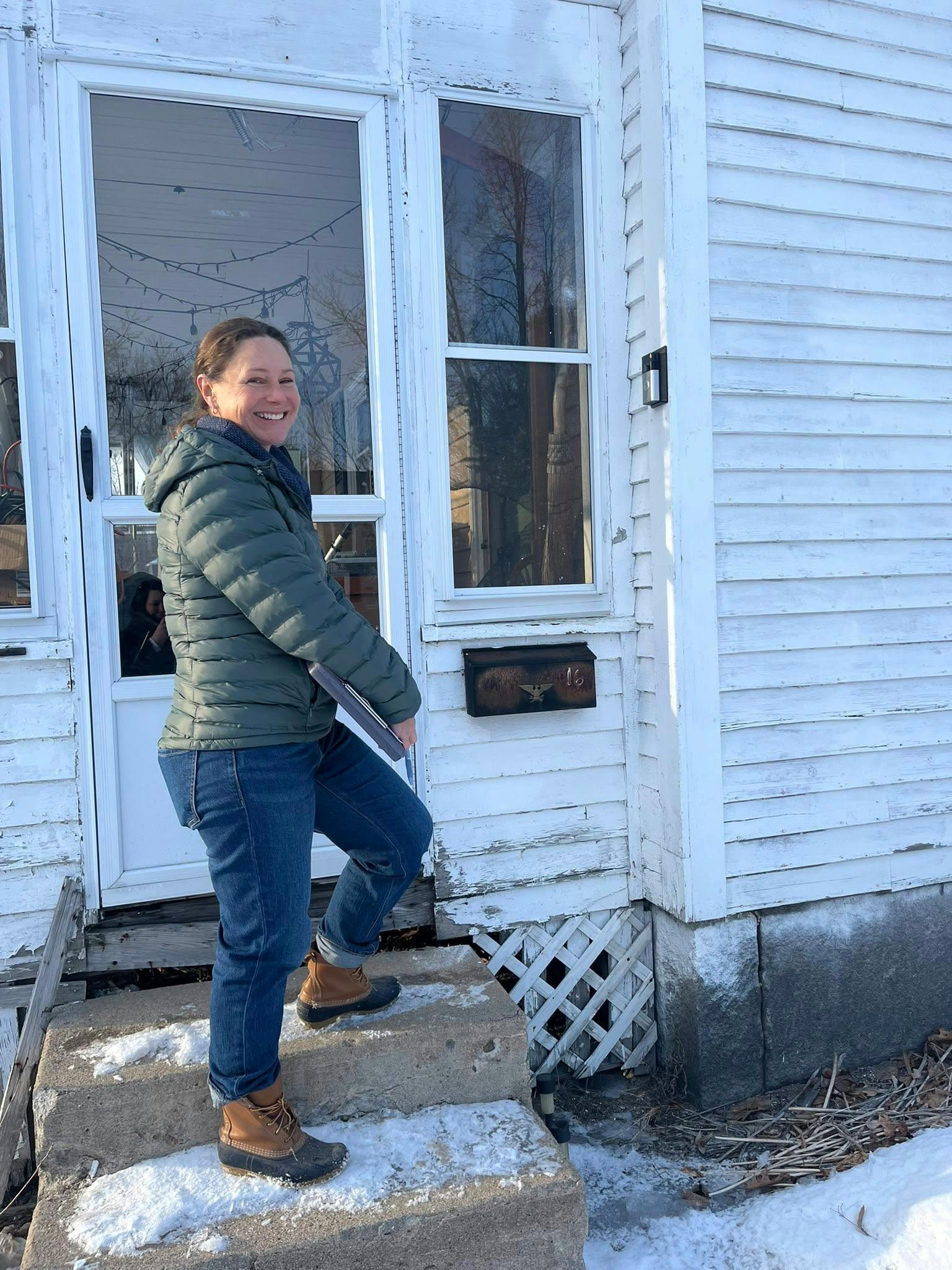 Candidate smiling and holding clipboard in front of door