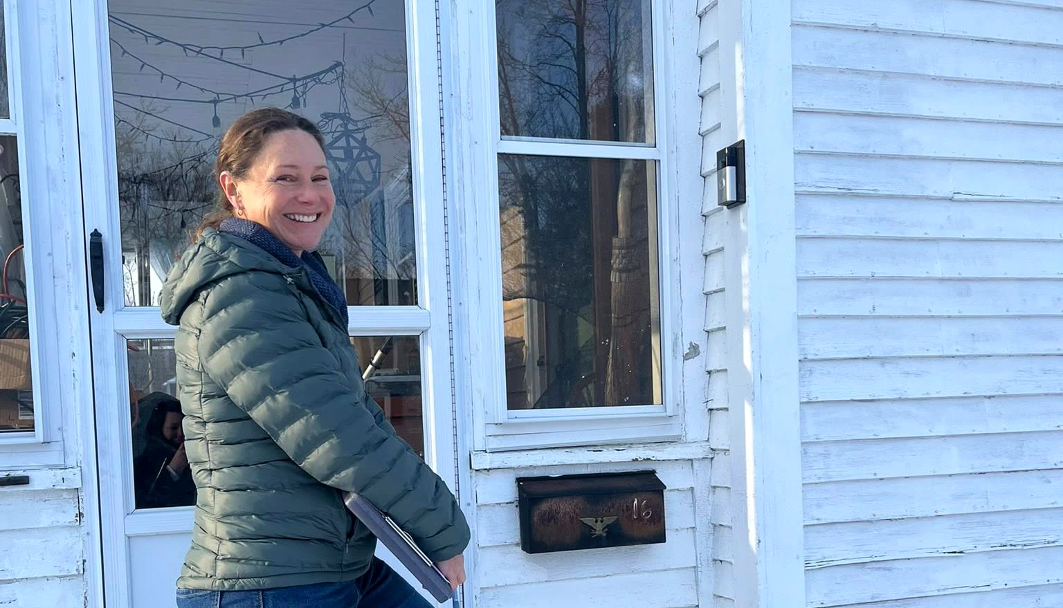 Candidate smiling and holding clipboard in front of door
