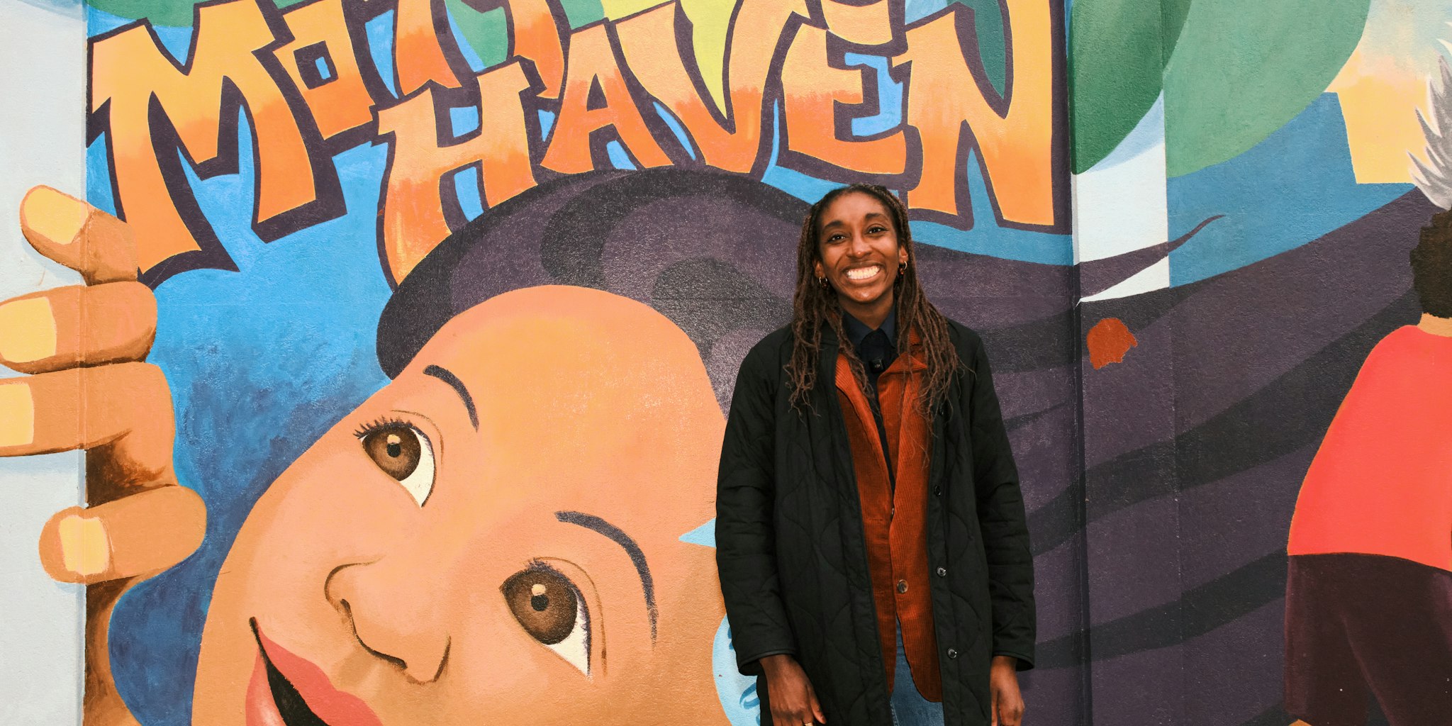 Christina Cover standing in front of a Mott Haven street mural