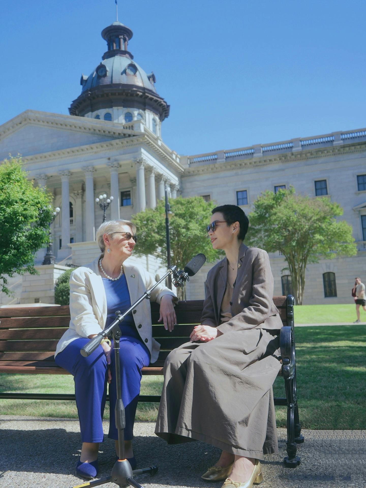 Edwina and Yili filming a podcast in front of the Statehouse