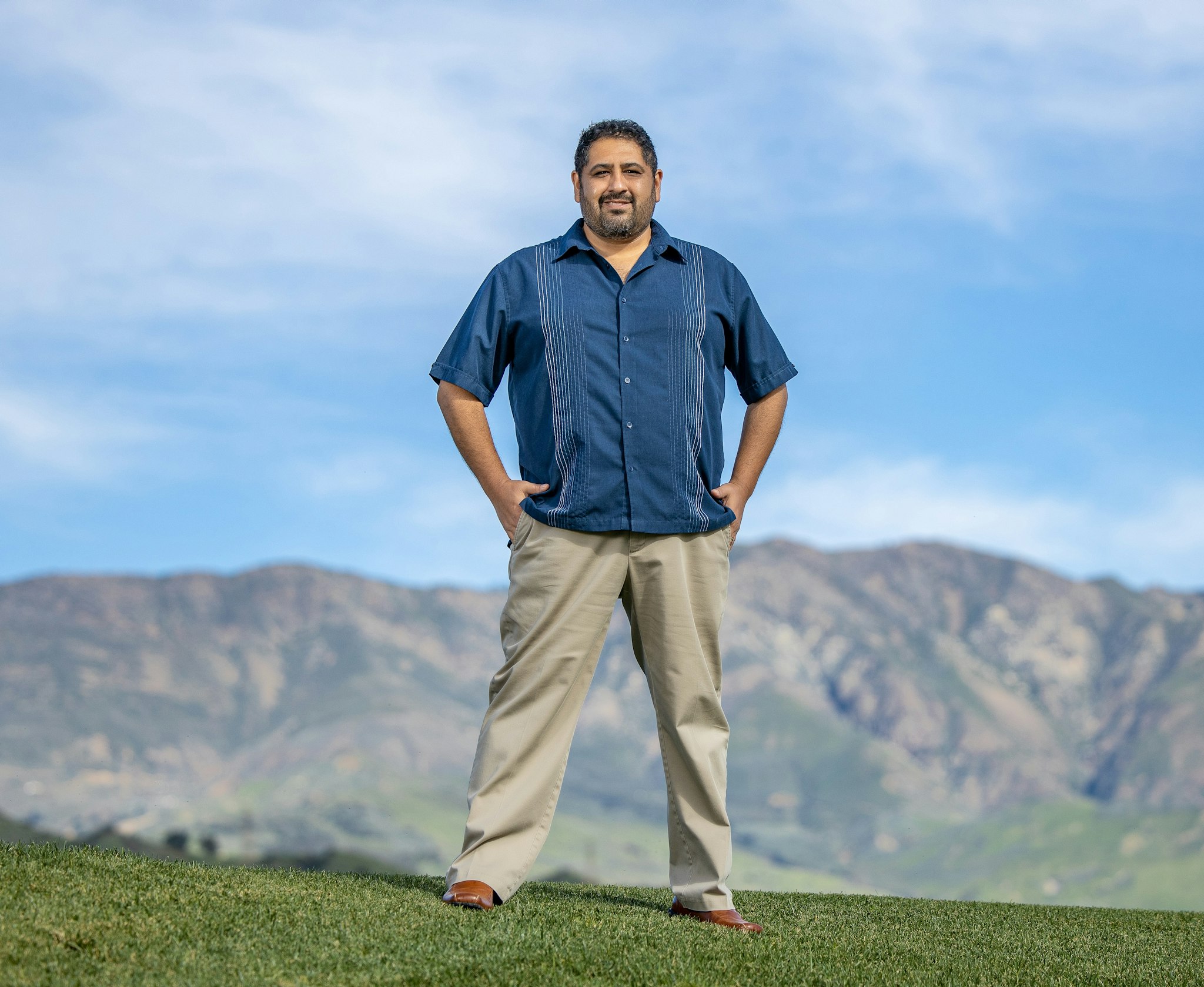 photo of Chris Espinosa, mountains on the background with clouds in the sky
