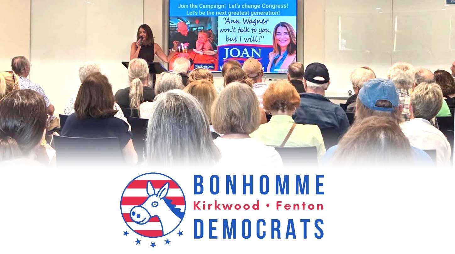 Photo of Joan VonDras, microphone in had, addressing the audience at the Bonhomme Democrats meeting