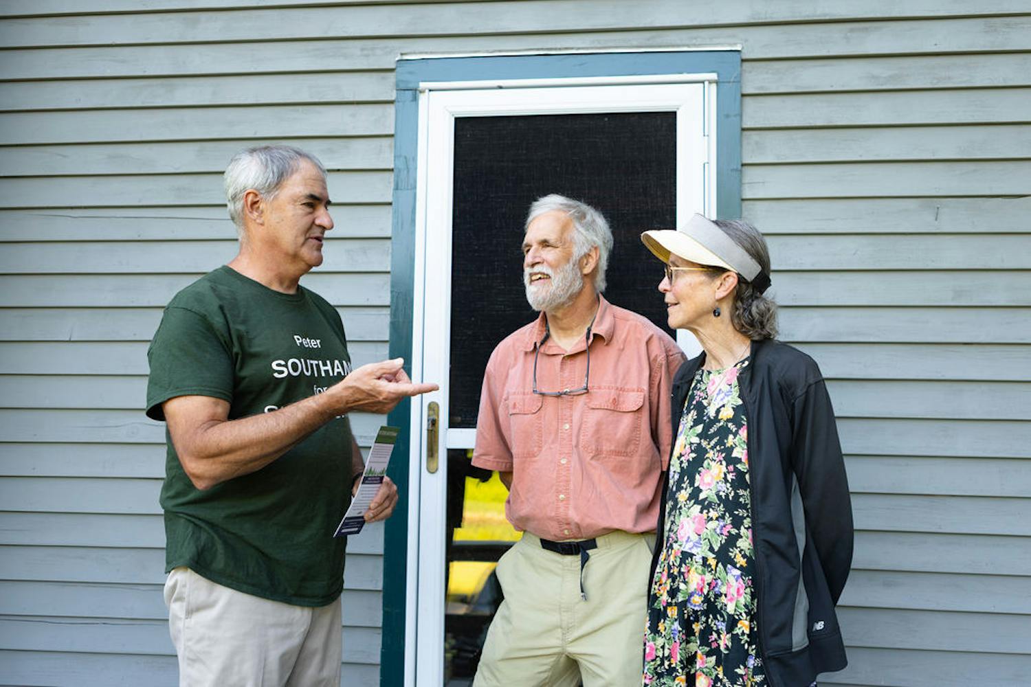 Candidate speaking with voters in front of house