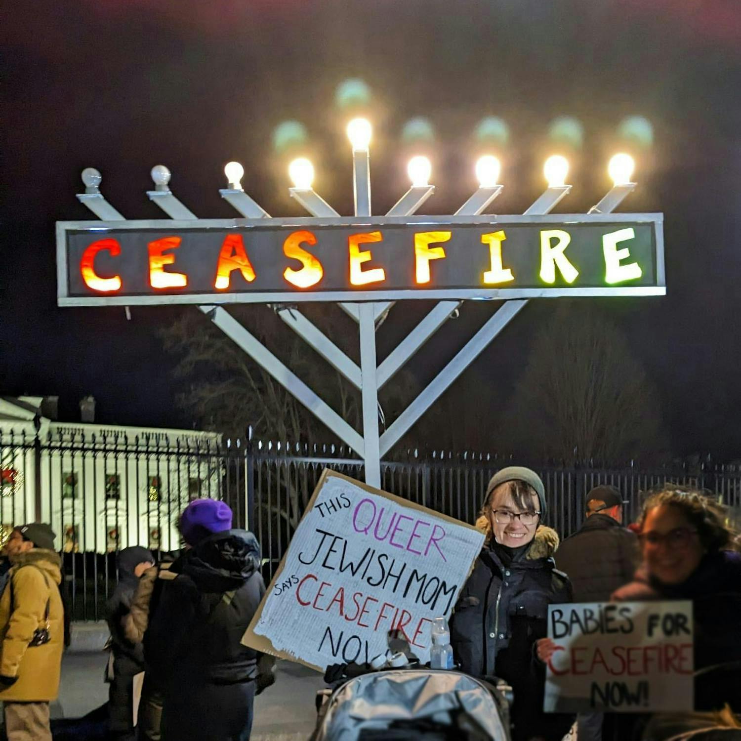 Foto de Alexis sosteniendo un cartel de protesta que dice "Mamá queer y judía por un Alto al fuego ahora".