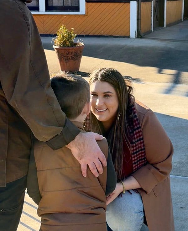 Sarah kneeling and smiling at young boy