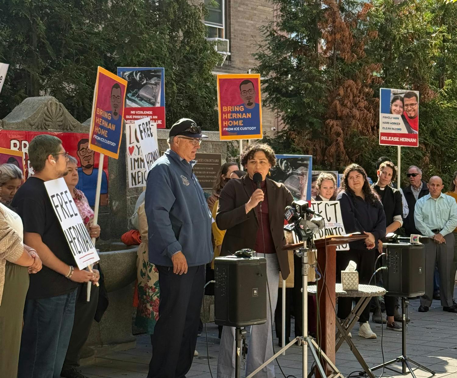Carey is standing at a rally for a community members' release from immigration detention, in front of a crowd holding signs