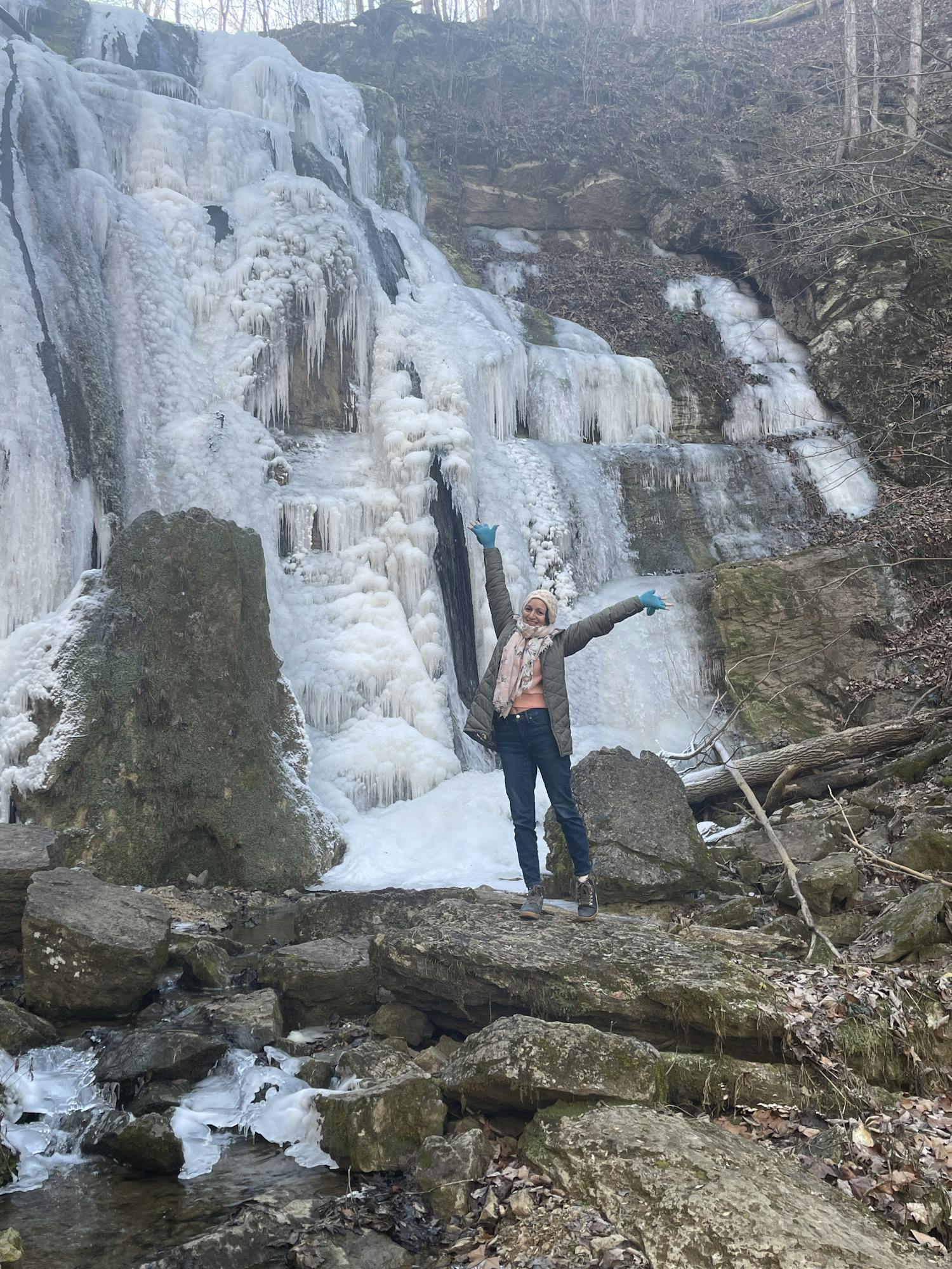 A woman standing in front of a frozen waterfall