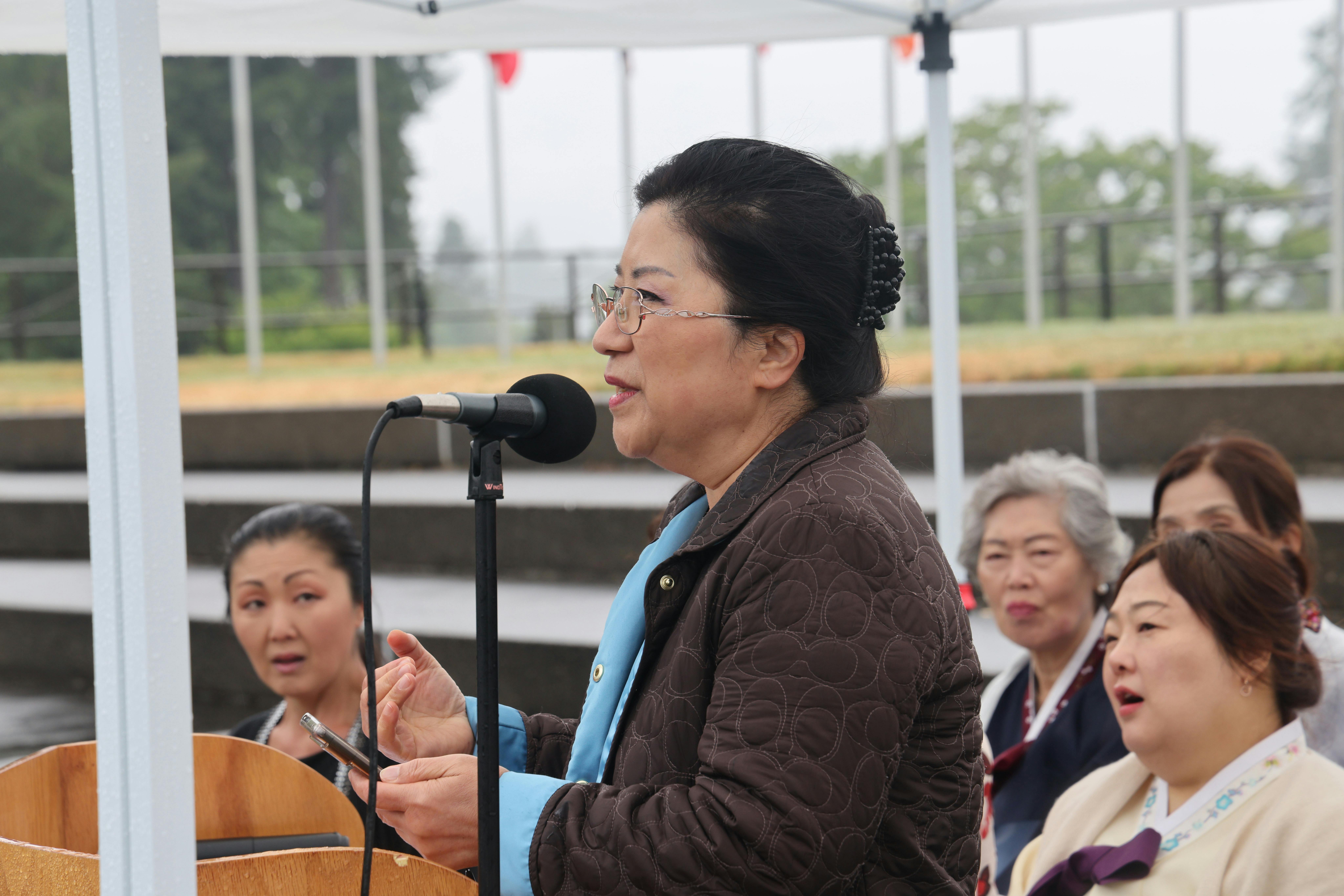 photo of Cindy Ryu standing at a microhpone surrounded by supporters