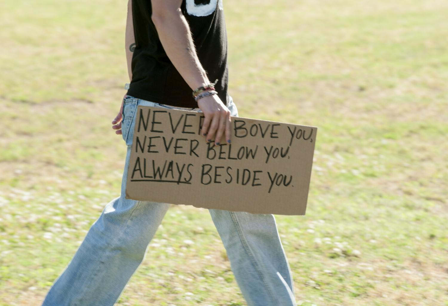 Protest sign that says "Never above you, never below you, ALWAYS beside you."