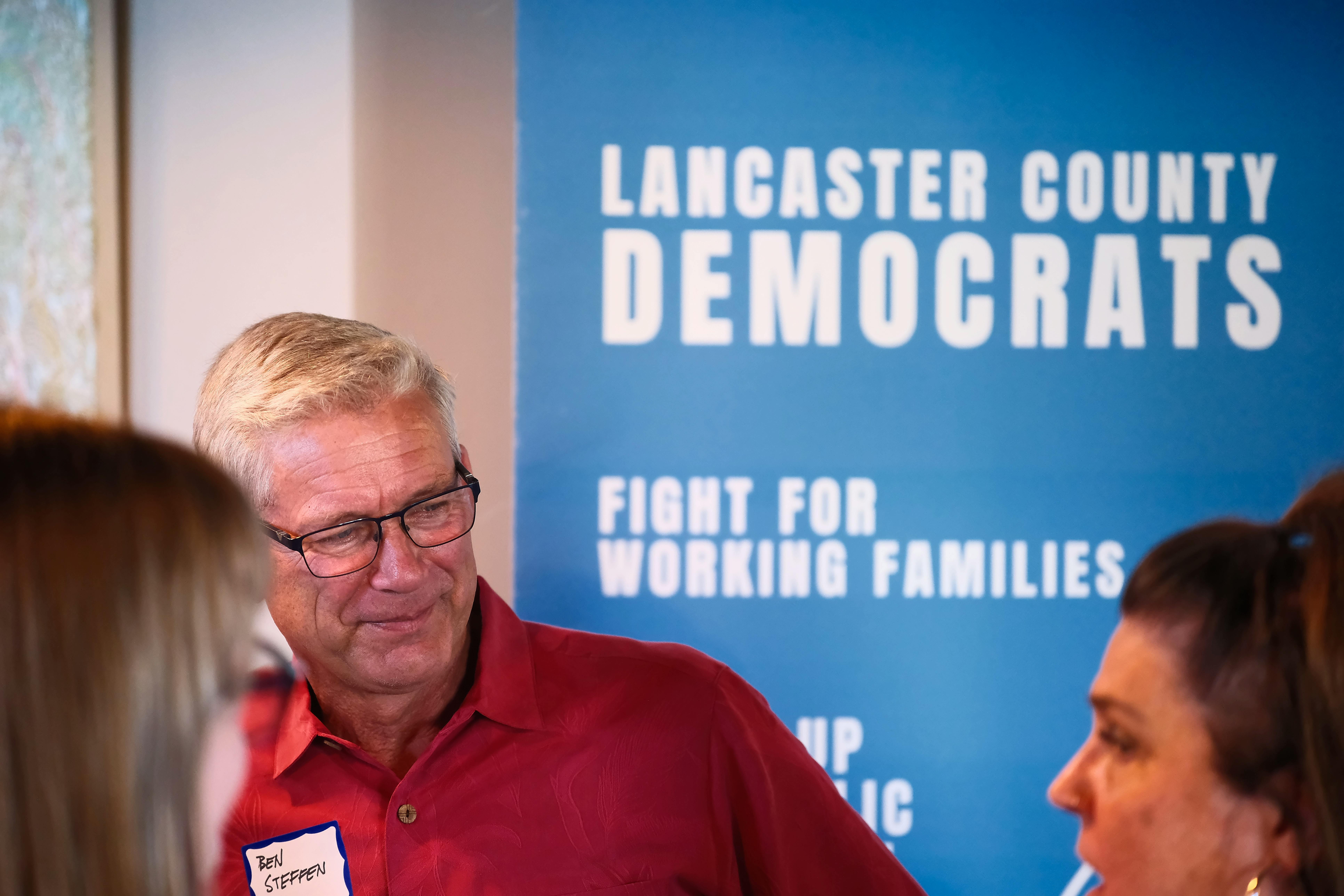 LCDP Event Banner with smiling man in red shirt and glasses looking at a brown haird woman